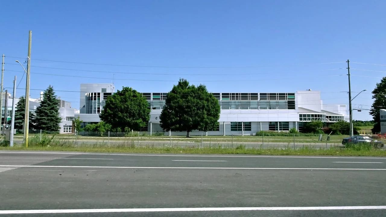 Durham College Whitby Campus building exterior with trees and an empty road; no people visible