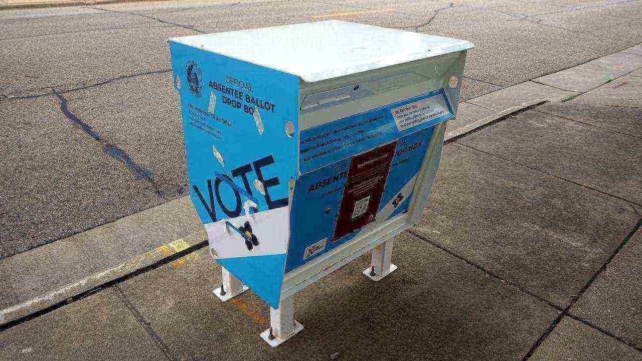 Close-up of an official absentee ballot drop box on a city sidewalk; no people visible