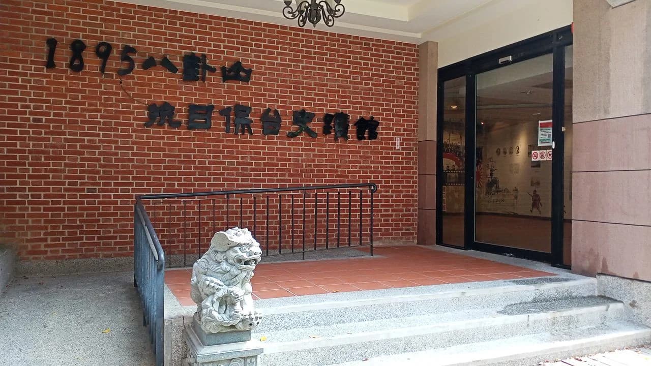 A wheelchair ramp with railings leading to the glass entrance of a public building.
