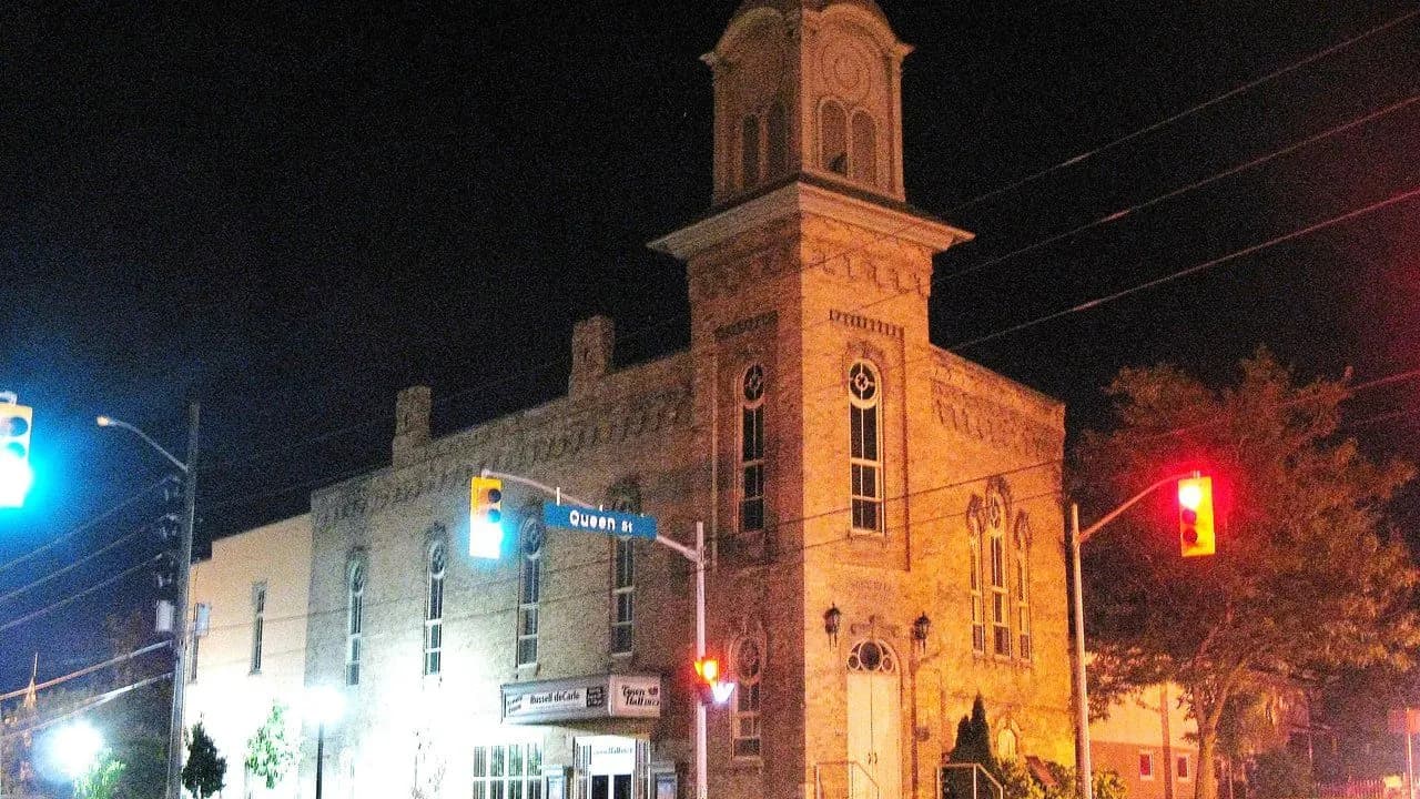 The former Port Perry Town Hall, a historic brick building with a clock tower, at night; no people visible.