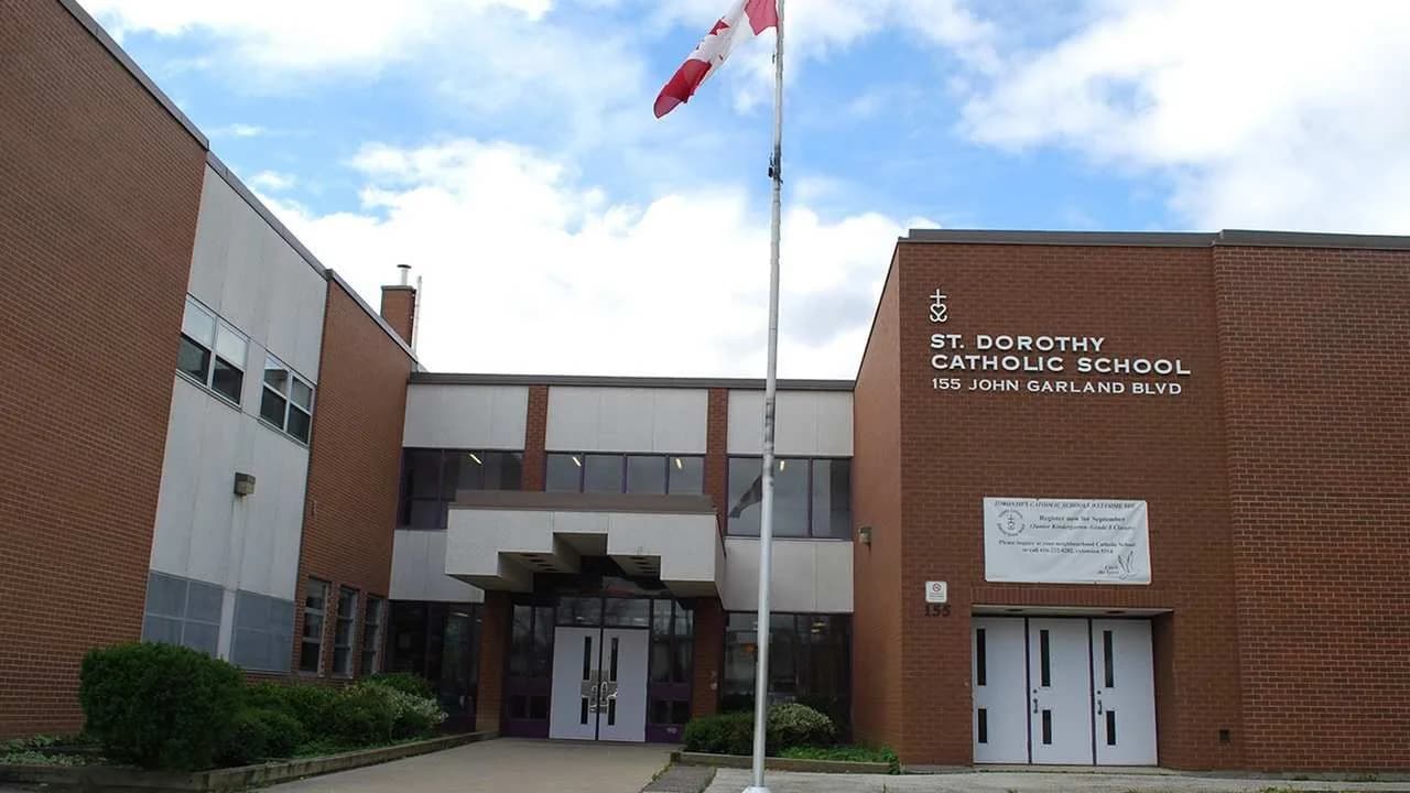 A brick Catholic elementary school building with a Canadian flag flying outside; no people visible.